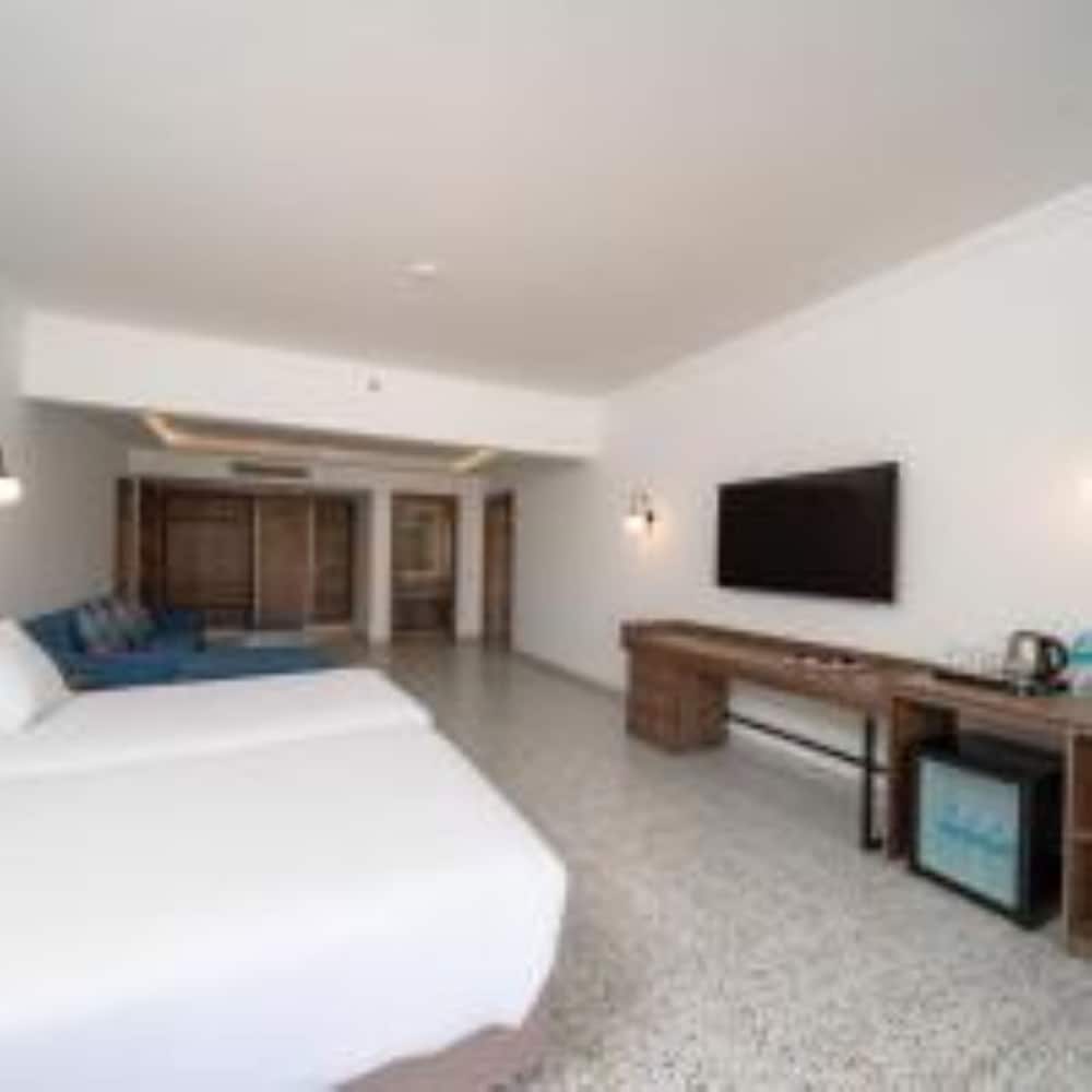 Pickalbatros Vita Resort Portofino guest room with a white bed and a wooden desk.