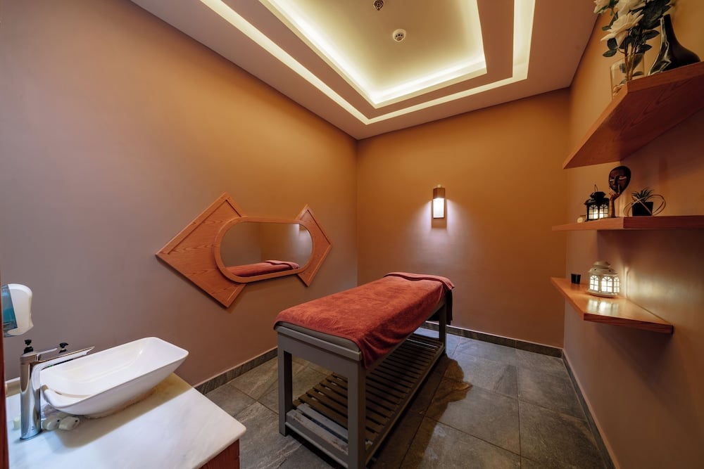 Pickalbatros Vita Resort Portofino spa treatment room with a massage table and wall shelves.