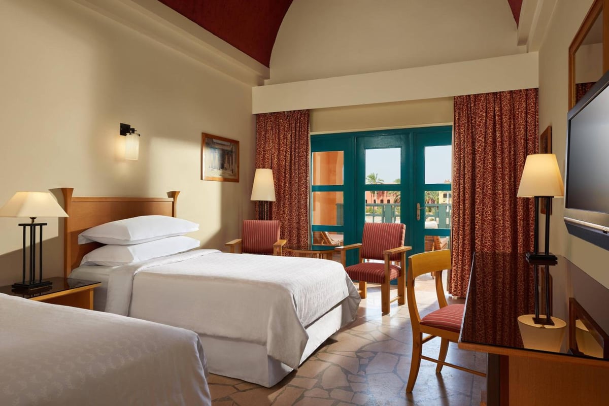 Sheraton Miramar Resort El Gouna guest room with two beds and glass doors.