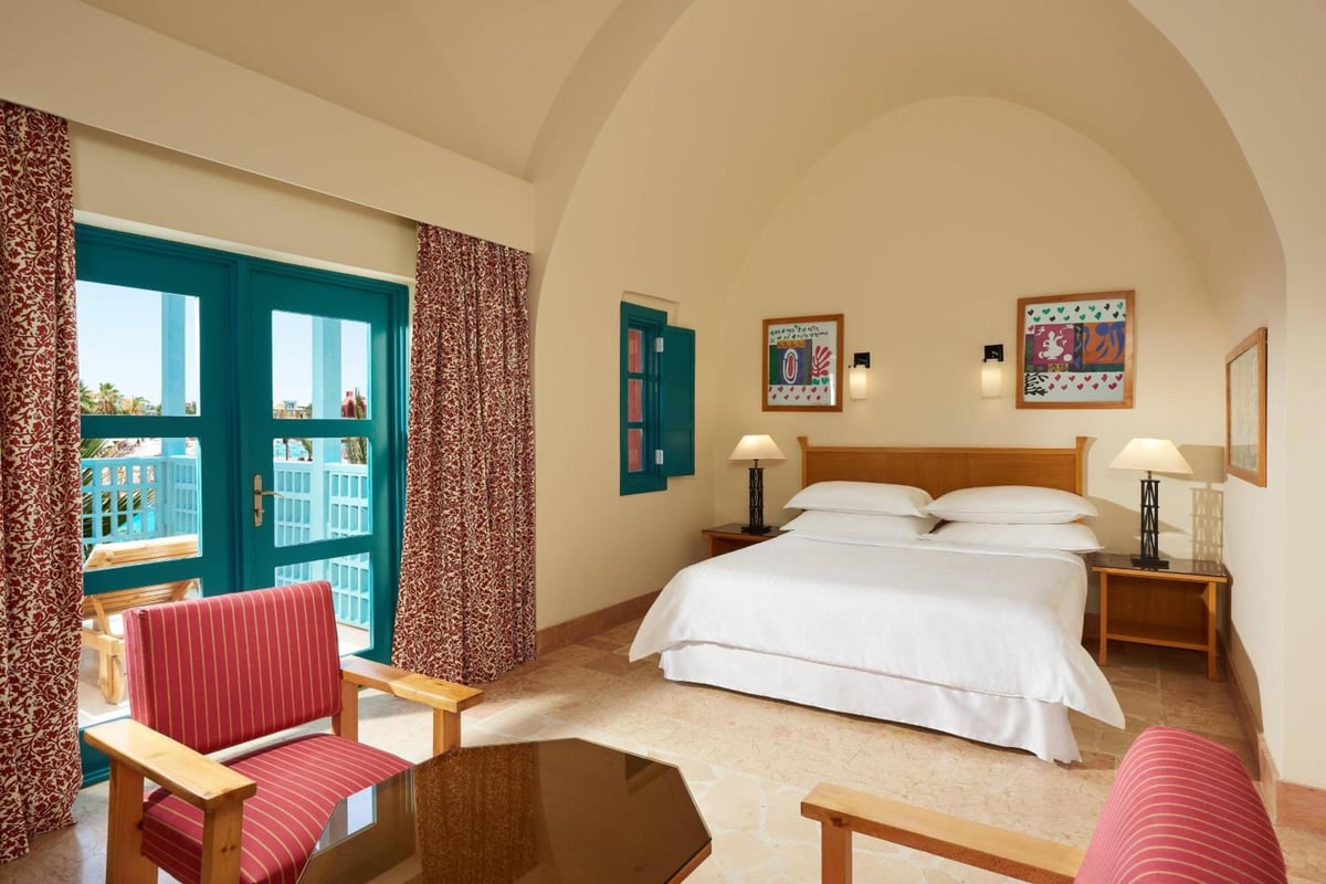 Sheraton Miramar Resort El Gouna bedroom with an arched ceiling and glass balcony doors.