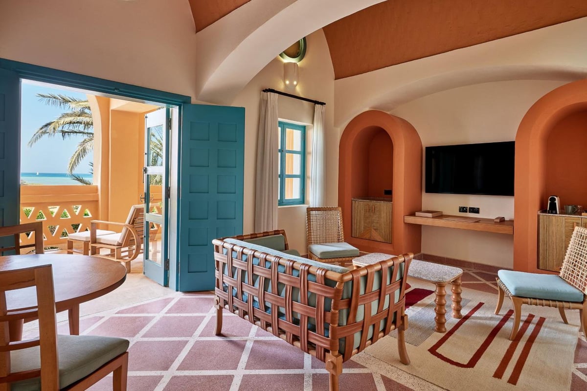 Sheraton Miramar Resort El Gouna living room with an arched TV alcove and open balcony doors.