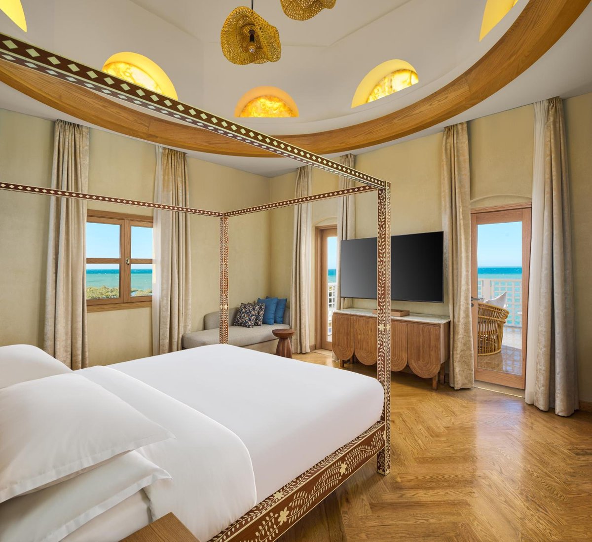 Sheraton Miramar Resort El Gouna bedroom with a four-poster bed and a balcony overlooking the sea.