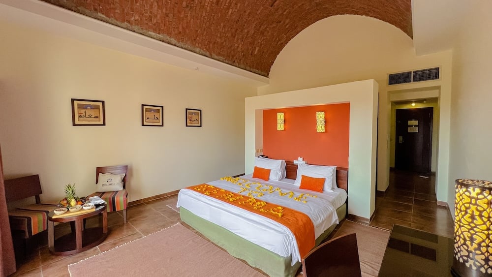 Gemma Resort bedroom with a vaulted brick ceiling and orange accent wall.