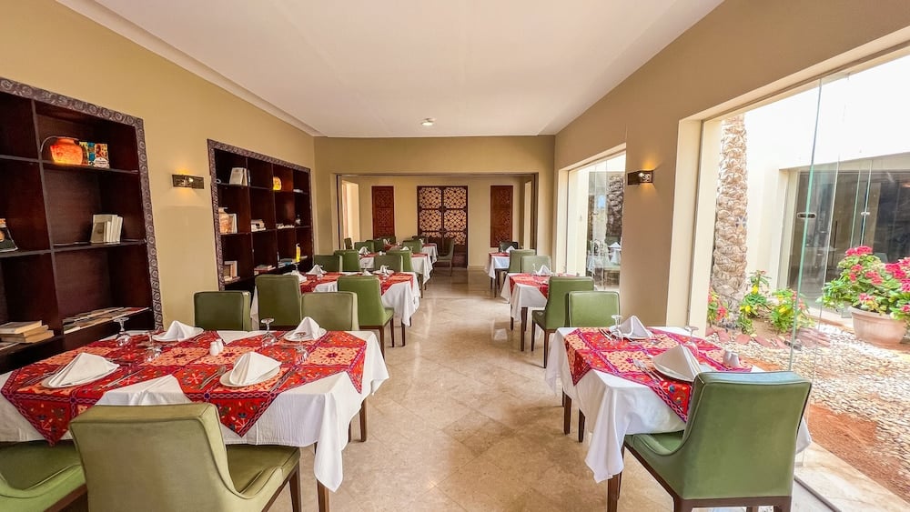 Gemma Resort dining room with red patterned tablecloths and green chairs.