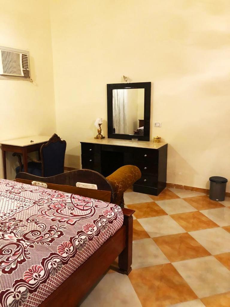 Nile Castle Luxor bedroom with a patterned bedspread and a dresser with a mirror.