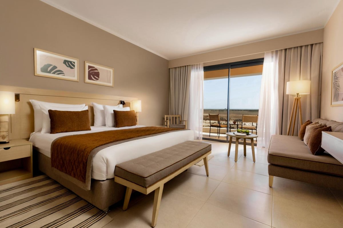 JAZ Elite Amara guest bedroom with a large bed and a sofa seating area.