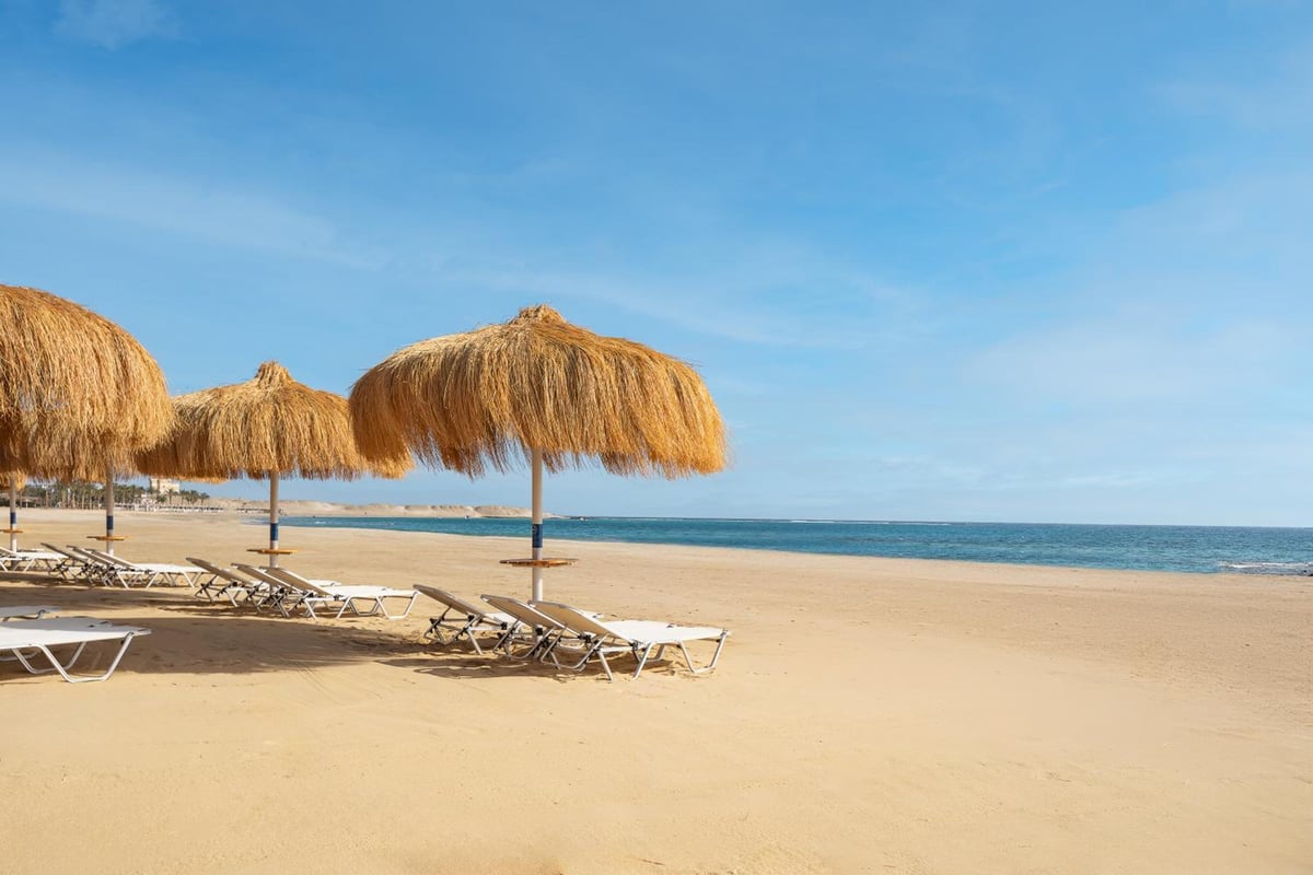 JAZ Elite Amara beach with thatched parasols and a sea view.