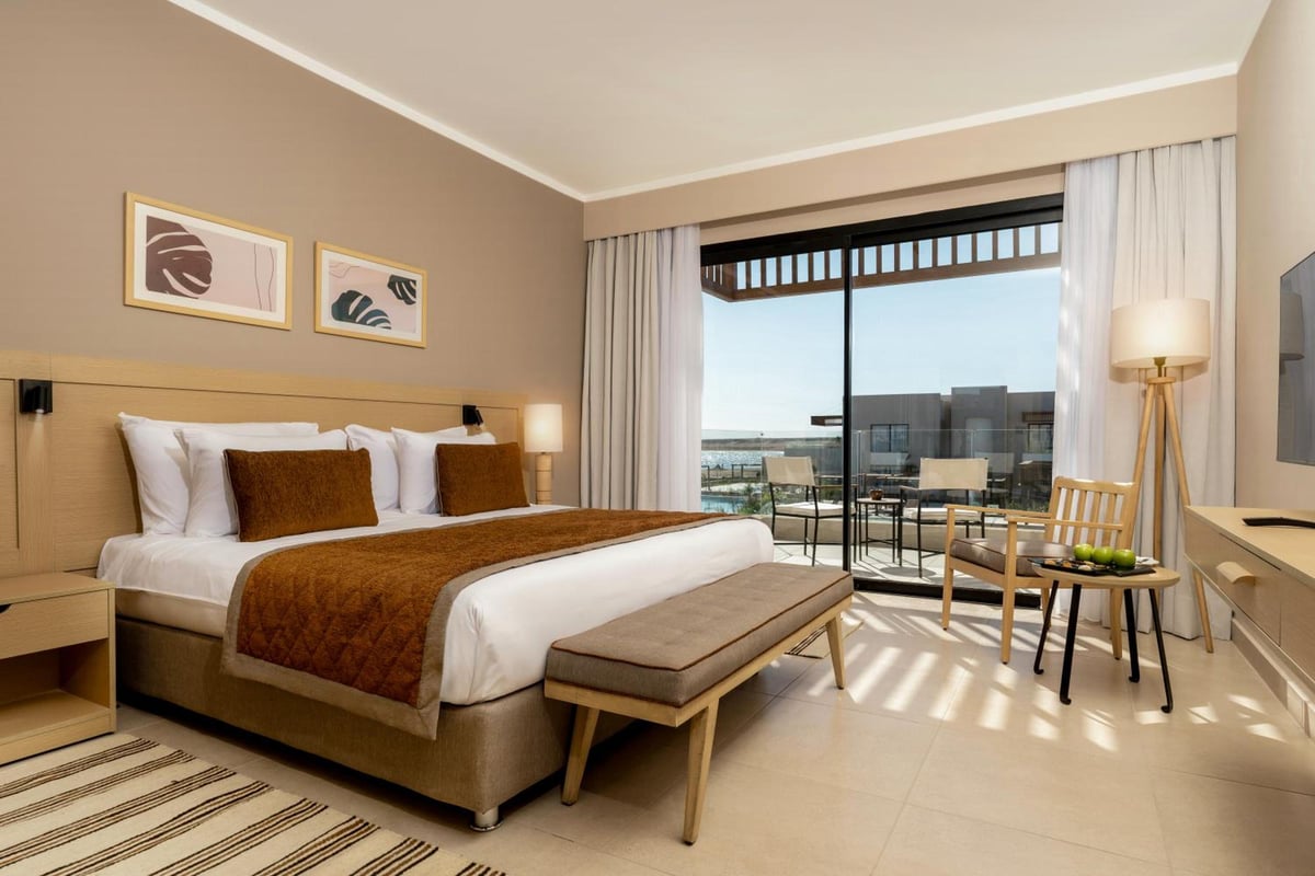 JAZ Elite Amara bedroom with a large bed and glass balcony doors.