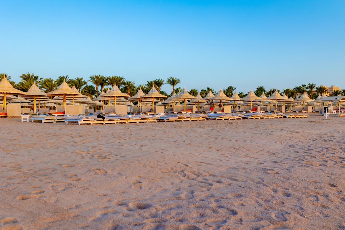 The Grand Resort Hurghada beach with thatched umbrellas and rows of loungers.