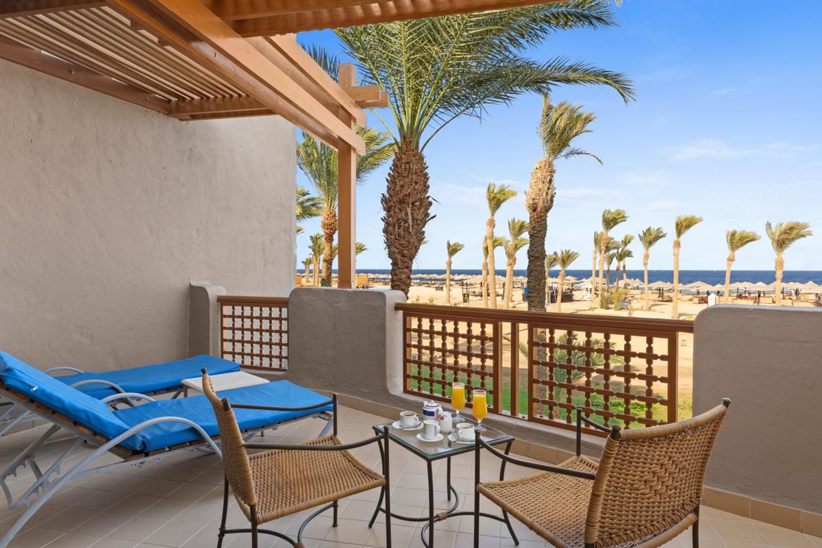 Pickalbatros Sands Port Ghalib terrace with blue loungers and palm trees.