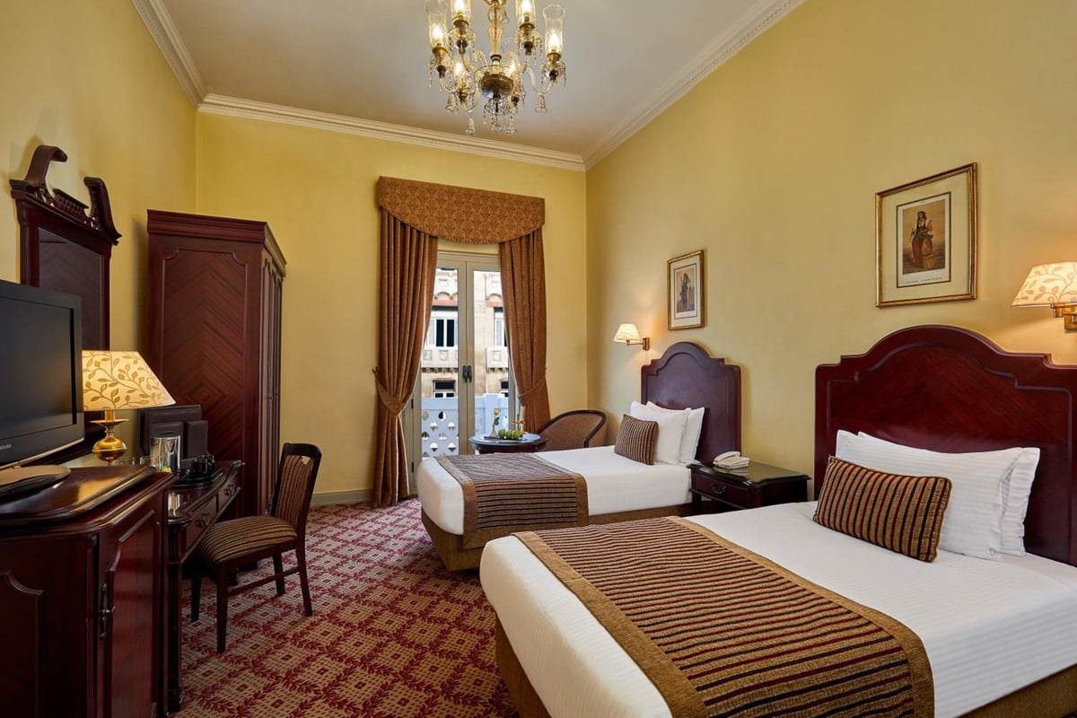 Steigenberger Cecil Hotel Alexandria twin bedroom with two beds and dark wood headboards.