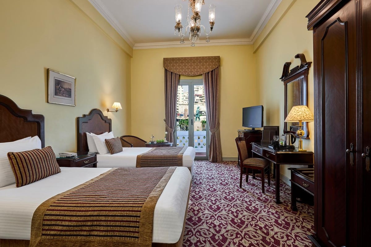 Steigenberger Cecil Hotel Alexandria guest room with twin beds and balcony doors.