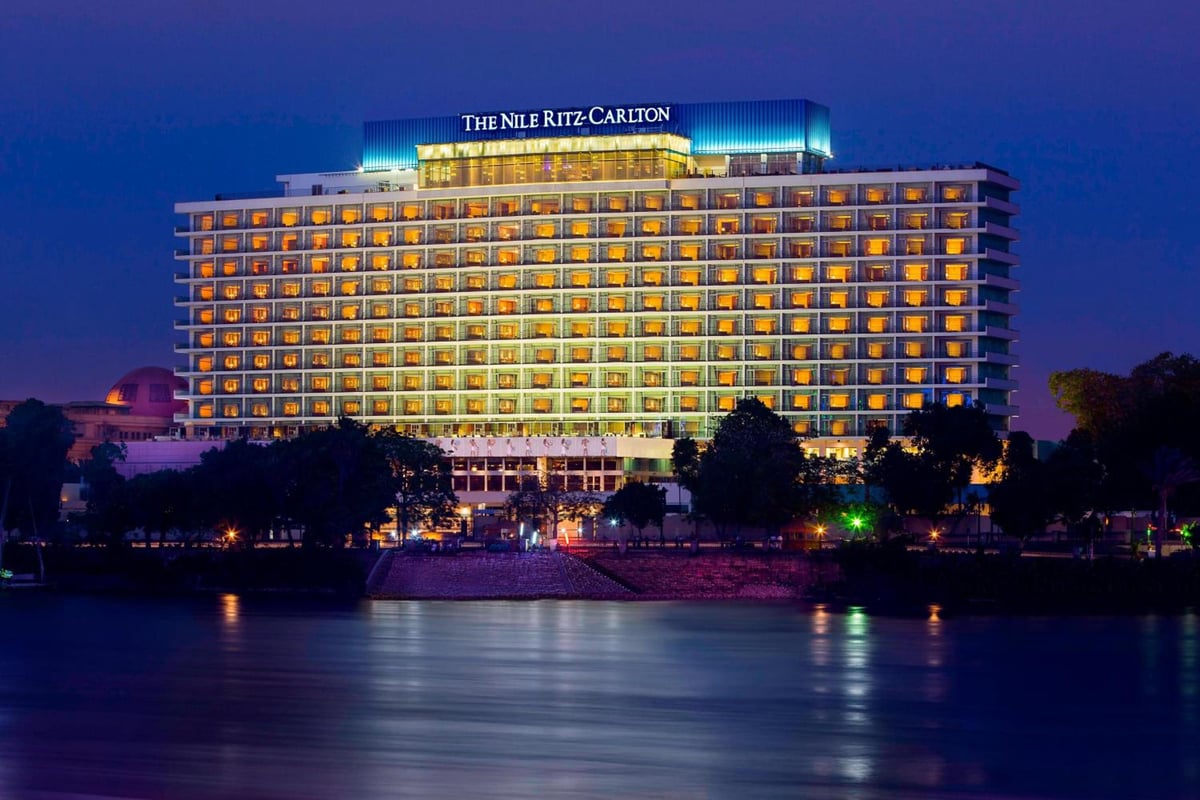Nile Ritz-Carlton Cairo exterior from the river with illuminated balconies and river reflections.