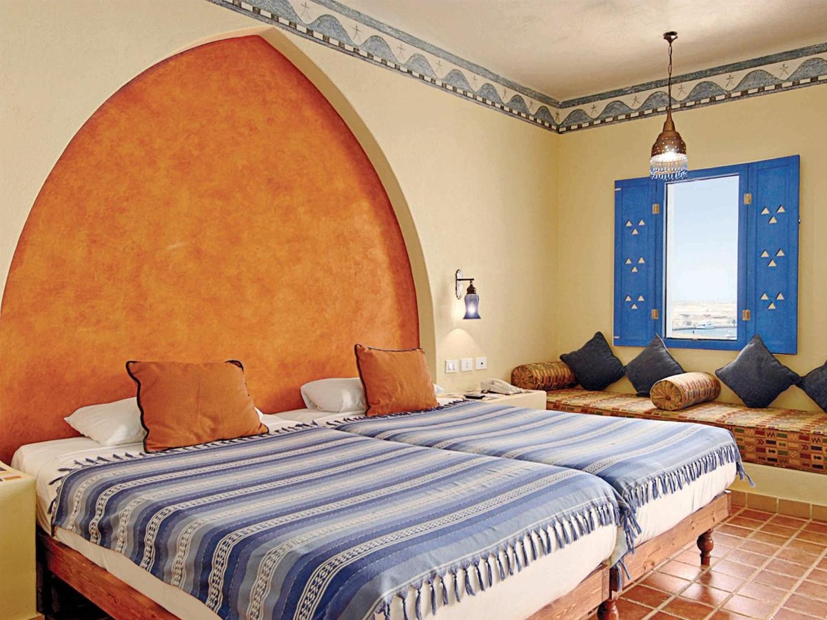 Marina Lodge at Port Ghalib twin bedroom with blue striped bedding and an orange arched wall.