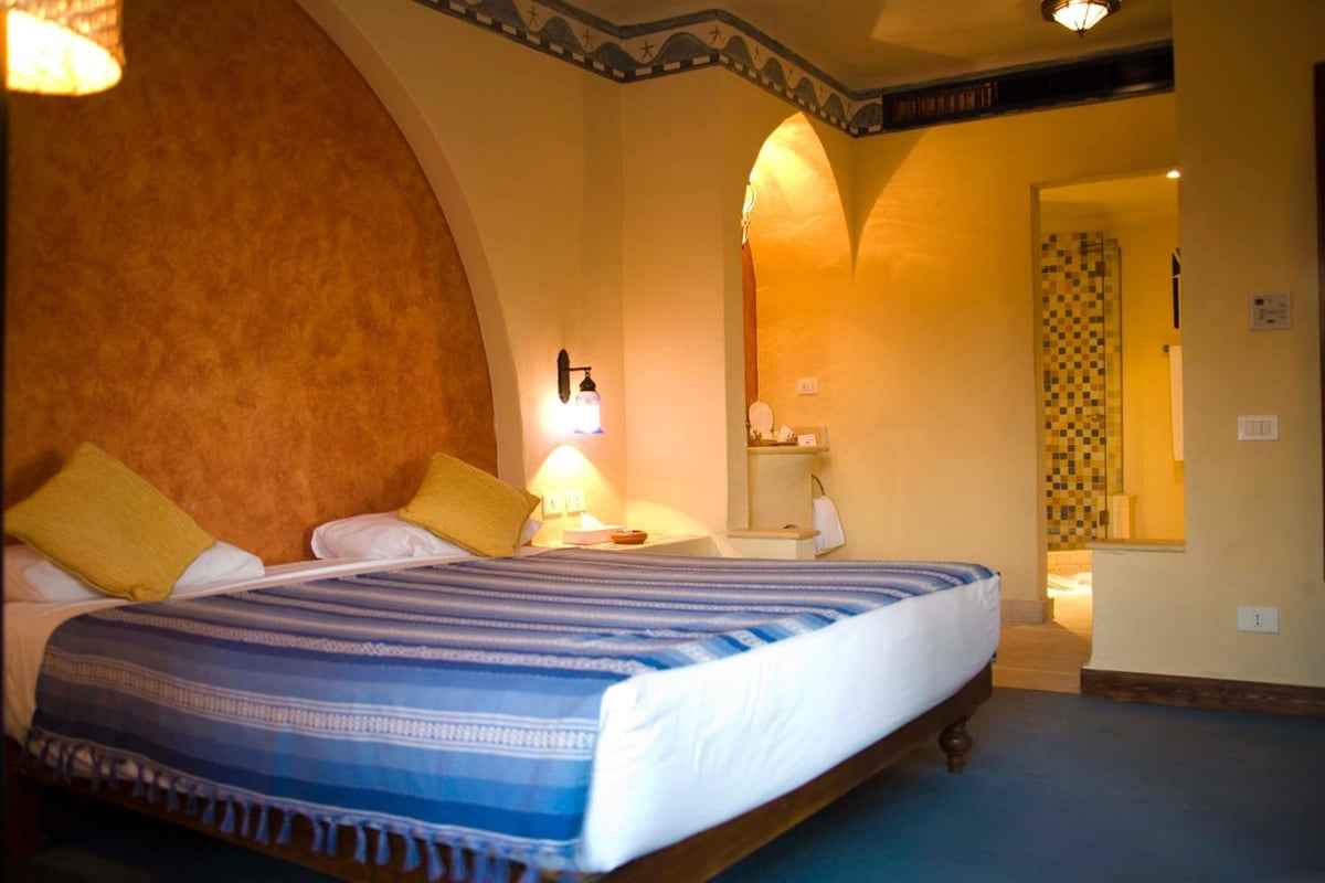 Marina Lodge at Port Ghalib bedroom with an arched wall and striped bedspread.