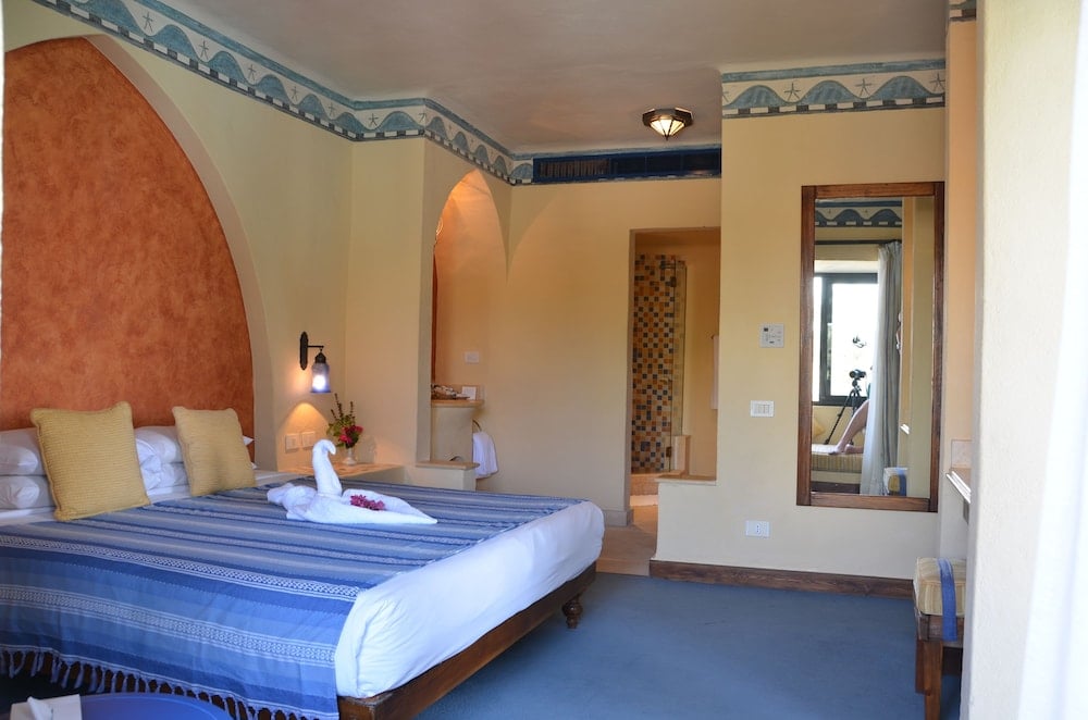 Marina Lodge at Port Ghalib guest room with a blue striped bed and arched walls.
