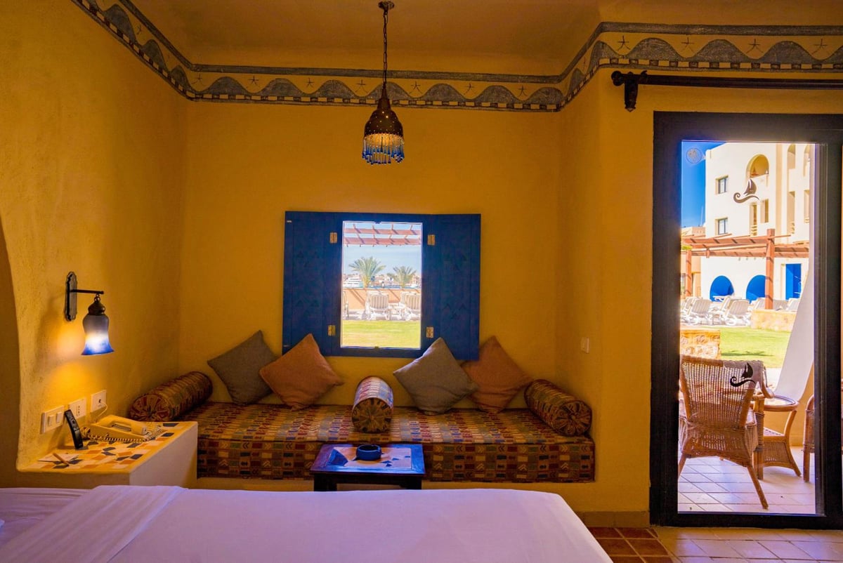 Marina Lodge at Port Ghalib guest room with a bed and cushioned window seating.