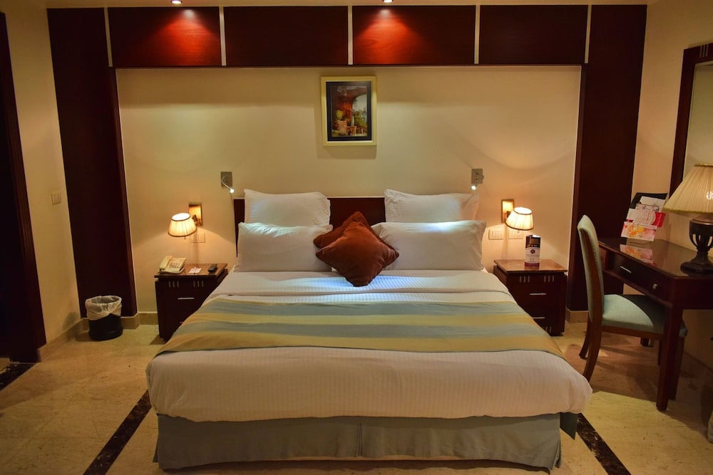 Romance Alexandria Hotel bedroom with a striped bedspread and dark wood headboard.