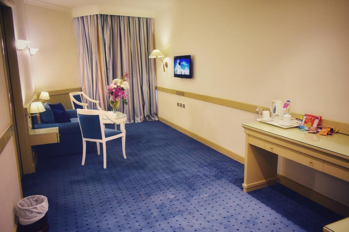 Romance Alexandria Hotel guest room with blue carpet and striped curtains.