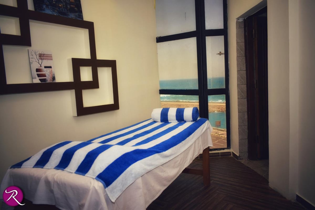 Romance Alexandria Hotel treatment room with a striped treatment bed and tall windows.