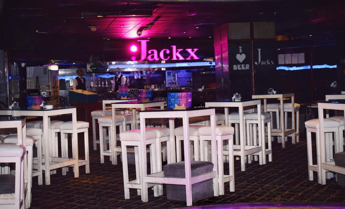 Romance Alexandria Hotel bar with white high tables and a pink neon sign.