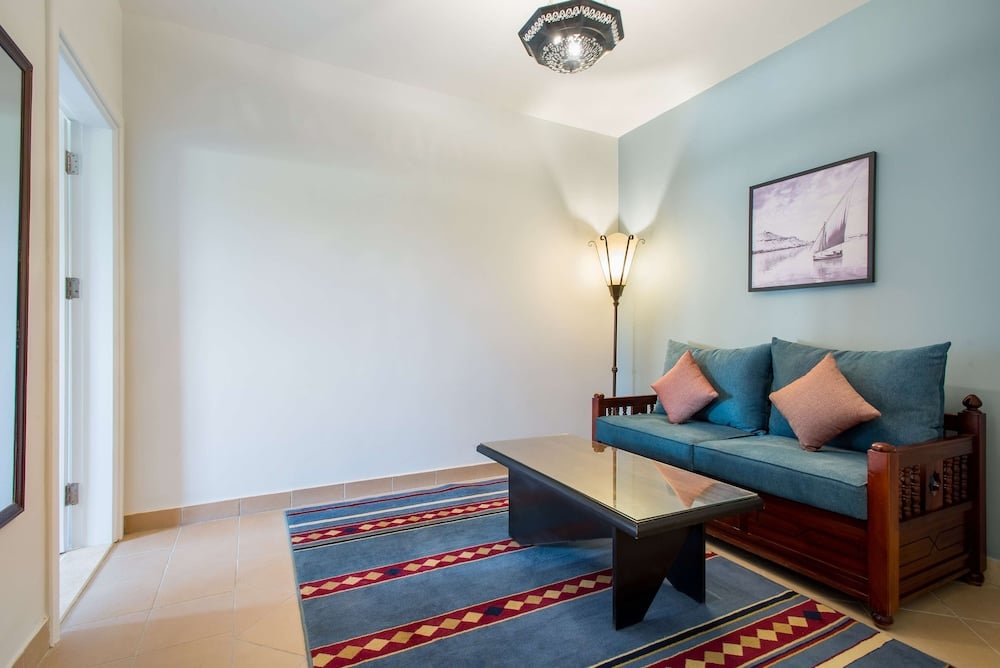 Marina Resort Port Ghalib sitting area with a blue sofa and a striped rug.