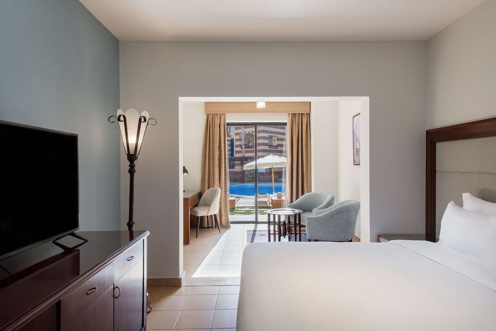 Marina Resort Port Ghalib bedroom with a white bed and adjoining sitting area.