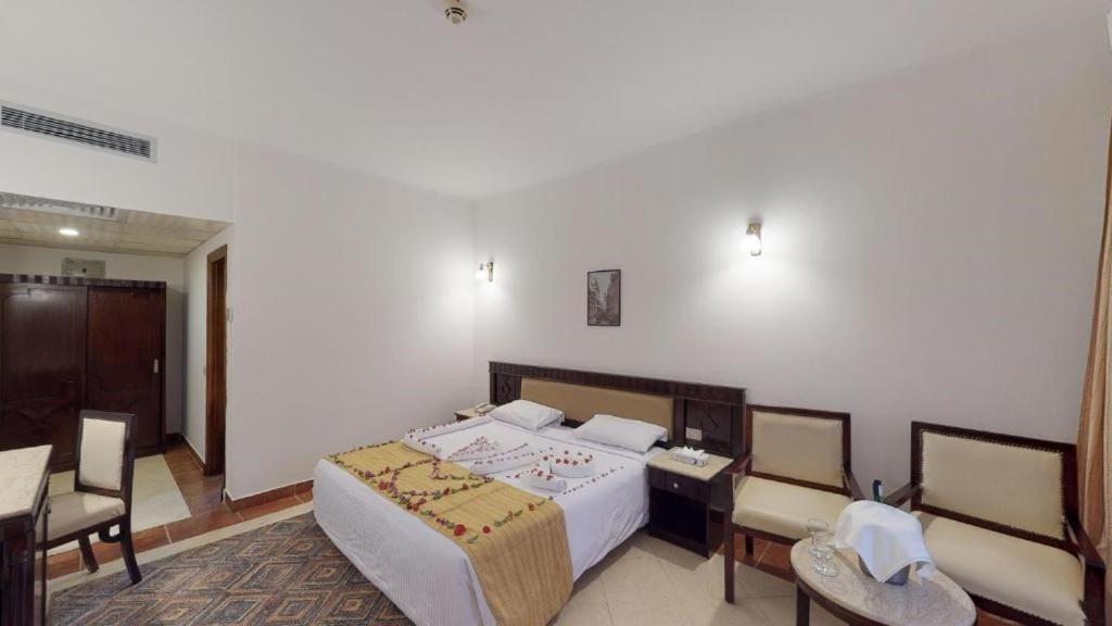 Falcon Naama Star Hotel bedroom with a double bed and chairs.