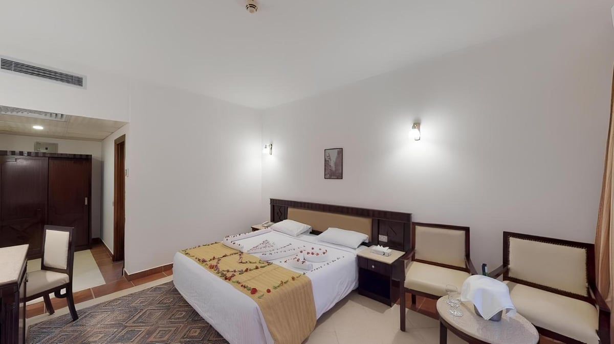 Falcon Naama Star Hotel bedroom with a double bed and chairs.