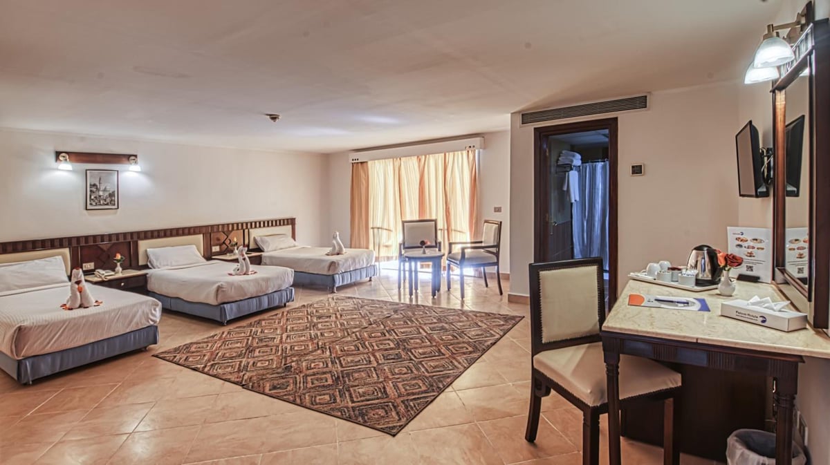 Falcon Naama Star Hotel guest room with four beds and a patterned rug.