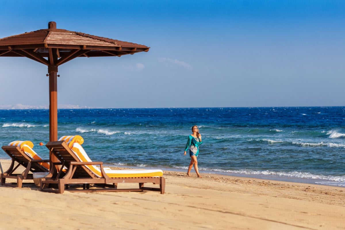 The Oberoi Sahl Hasheesh beach with wooden loungers and blue sea.