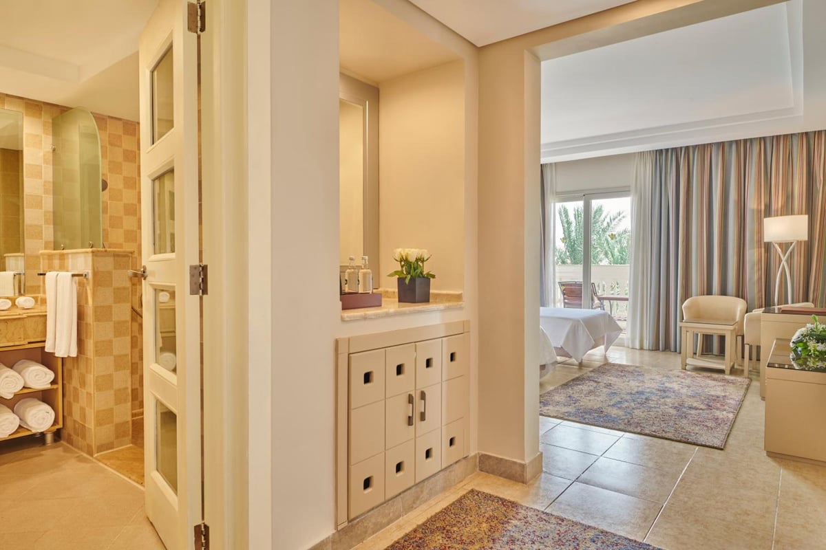 Rixos Premium Seagate suite interior with a tiled shower and curtained bedroom.
