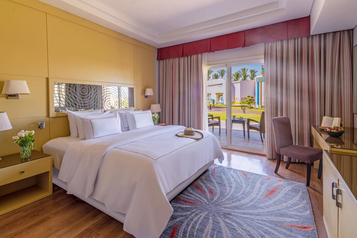 Rixos Premium Seagate guest bedroom with a king-size bed and sliding glass doors.