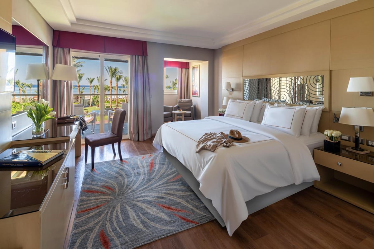 Rixos Premium Seagate bedroom with a large bed and balcony doors.