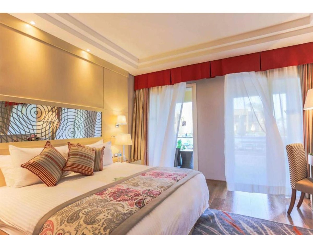 Rixos Premium Seagate guest bedroom with a large bed and floor-to-ceiling windows.
