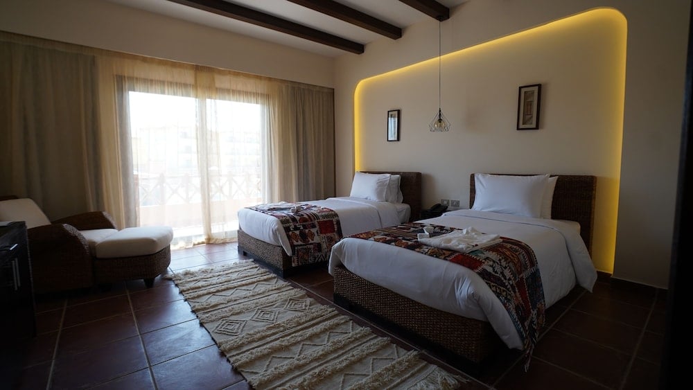 Amarina Jannah Resort & Aqua Park twin bedroom with two beds and a curved, illuminated headboard.