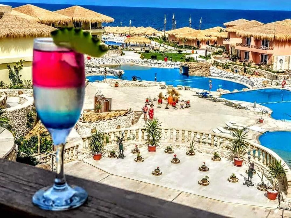 Amarina Jannah Resort & Aqua Park outdoor pool area with a curved pool and thatched-roof buildings.