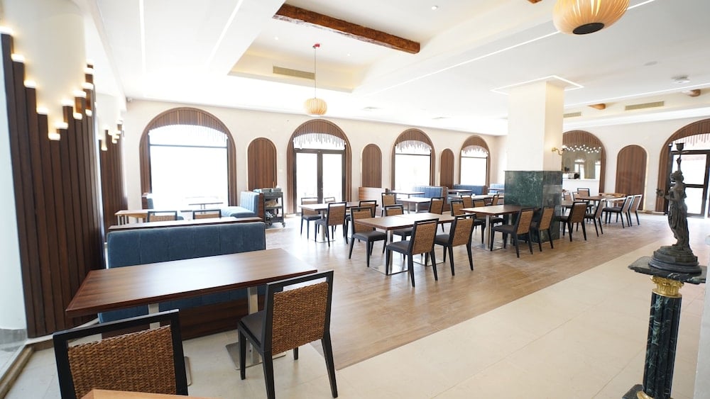 Amarina Jannah Resort & Aqua Park dining room with arched windows and wooden tables.