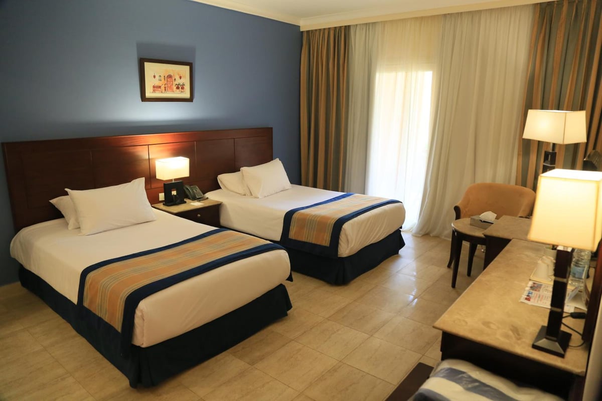 Stella Beach Resort & Spa Makadi Bay guest room with twin beds and blue walls.