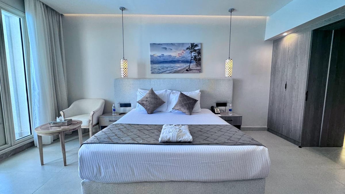 Stella Beach Resort & Spa Makadi Bay bedroom with a large bed and floor-to-ceiling windows.