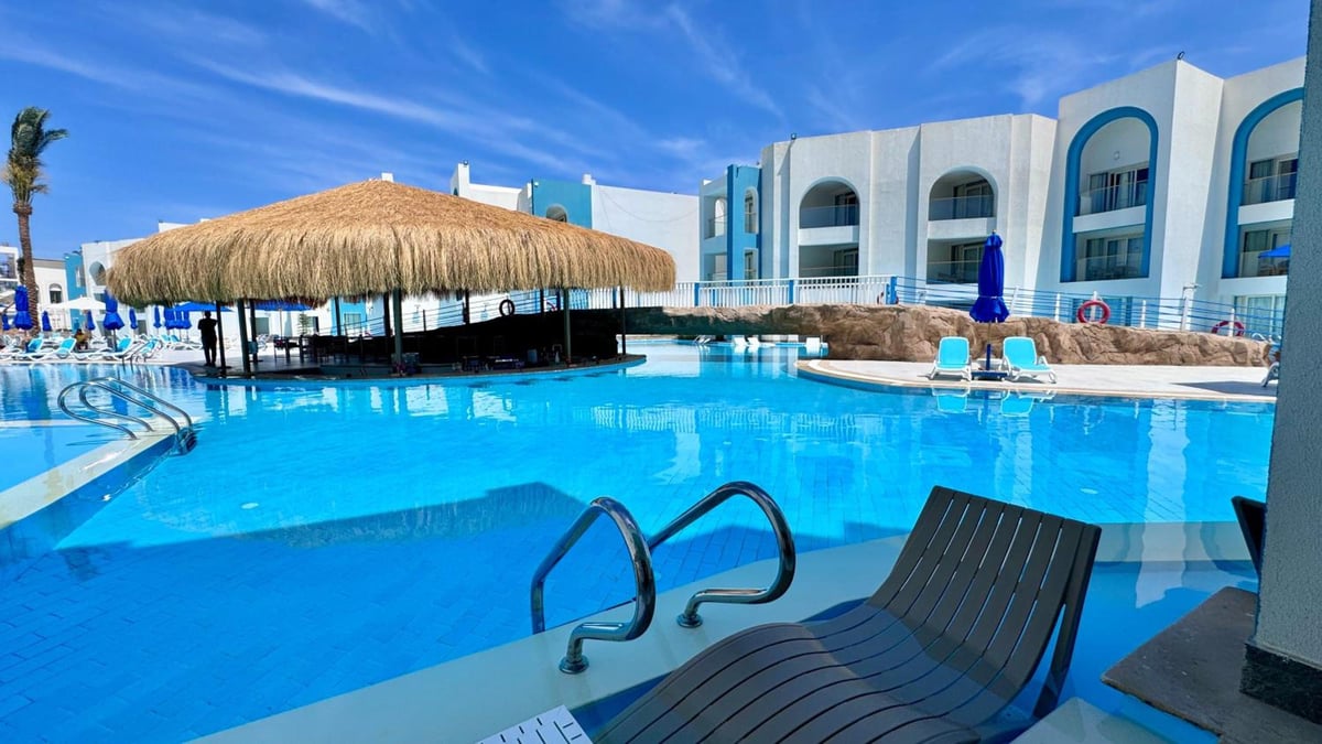 Stella Beach Resort & Spa Makadi Bay pool with in-water loungers and a thatched-roof bar.