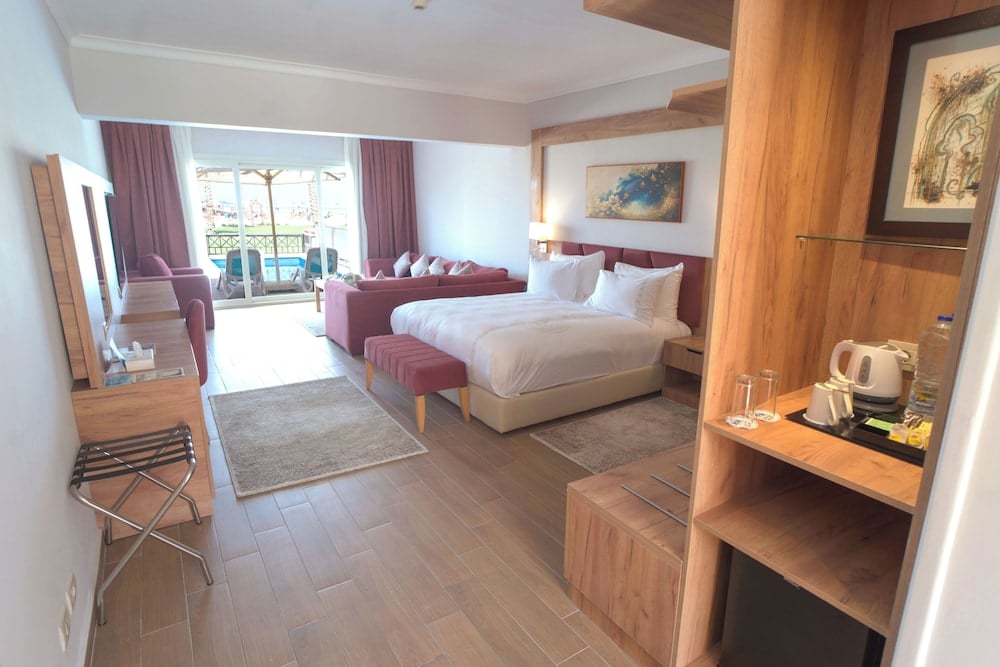 Stella Beach Resort & Spa Makadi Bay guest room with a bed and sofa.
