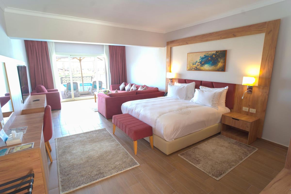 Stella Beach Resort & Spa Makadi Bay guest room with a king bed and sliding glass doors.