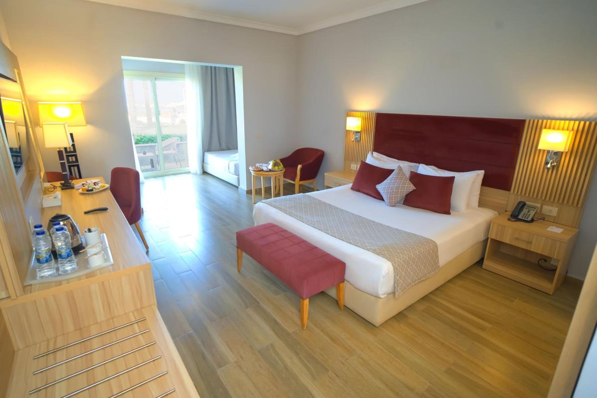 Stella Beach Resort & Spa Makadi Bay bedroom with a large bed and balcony doors.