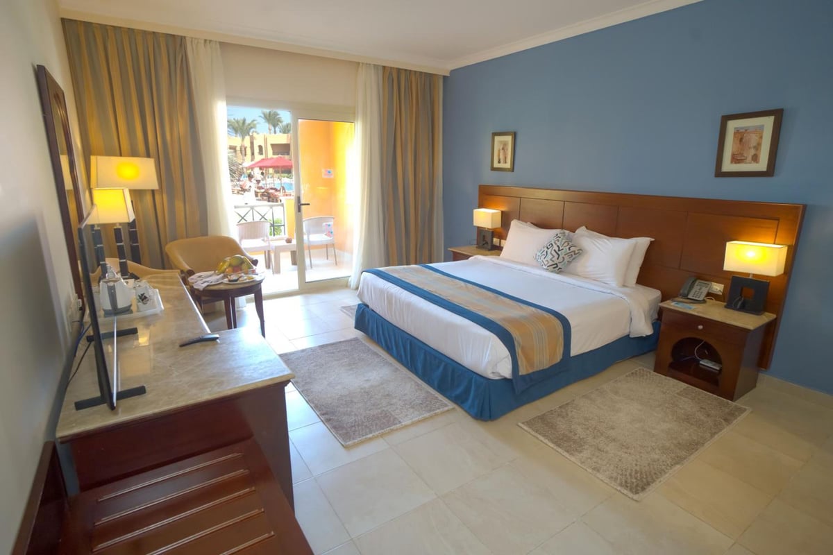 Stella Beach Resort & Spa Makadi Bay guest room with a bed and balcony.