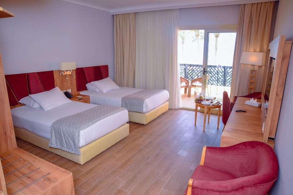 Stella Beach Resort & Spa Makadi Bay guest room with two twin beds and sliding glass doors.