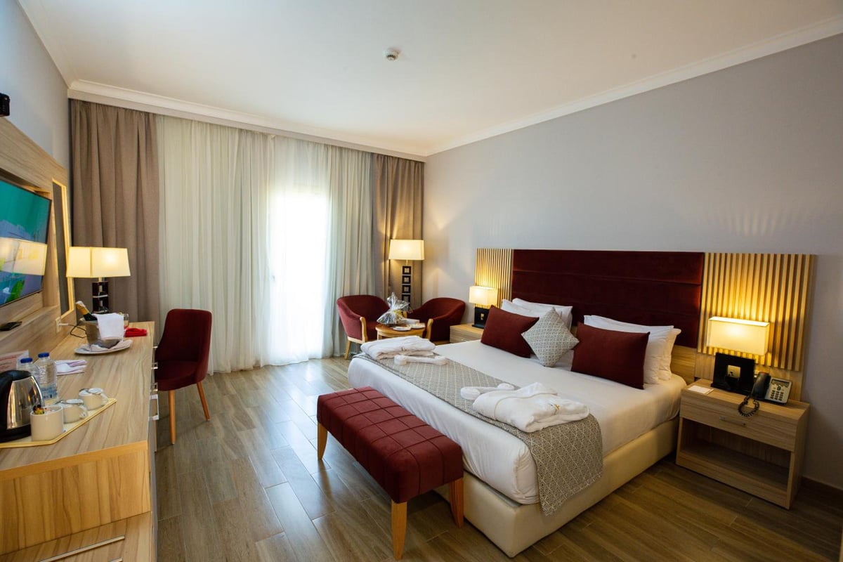 Stella Beach Resort & Spa Makadi Bay bedroom with a large bed and full-length curtains.