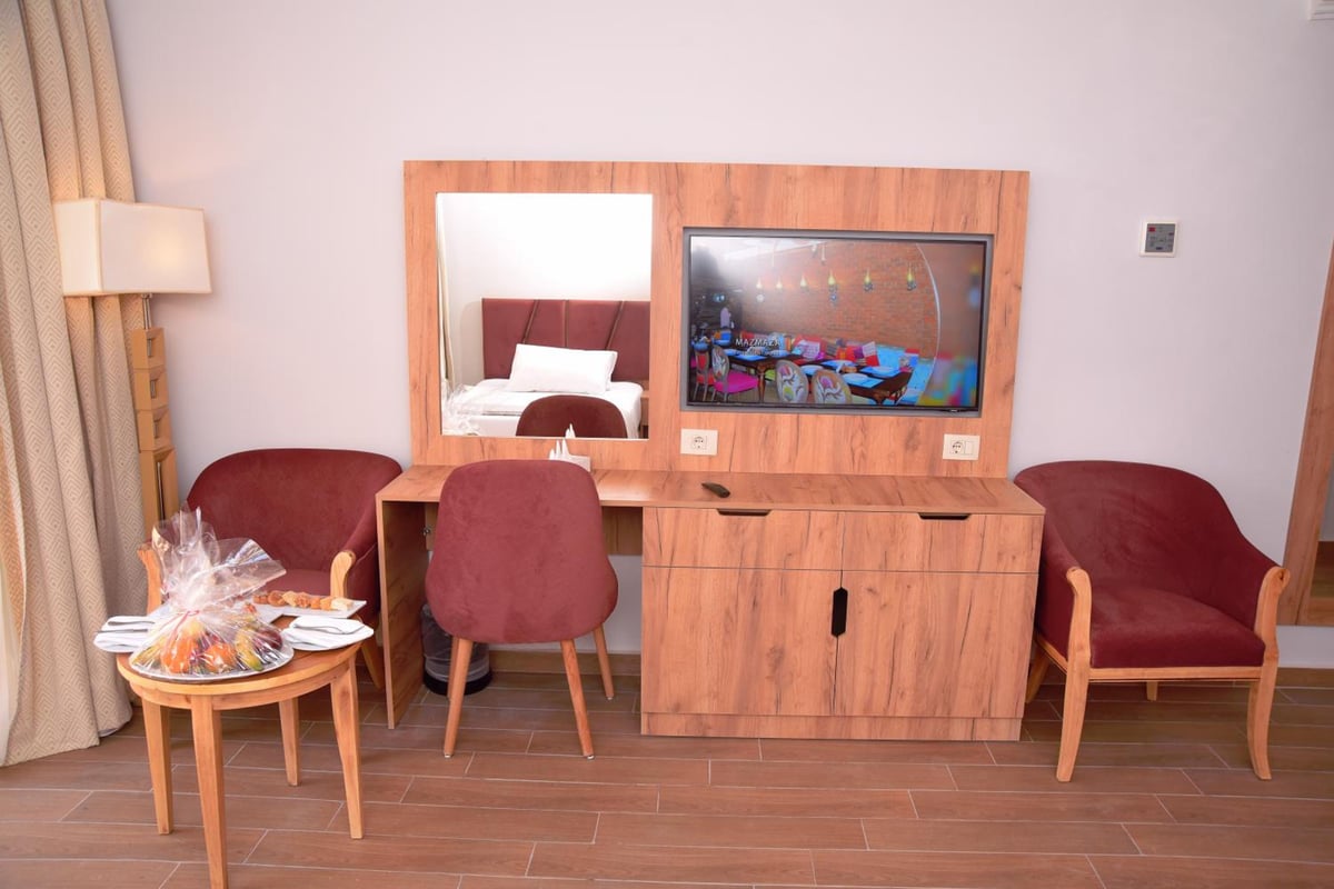 Stella Beach Resort & Spa Makadi Bay guest room with a television and upholstered chairs.