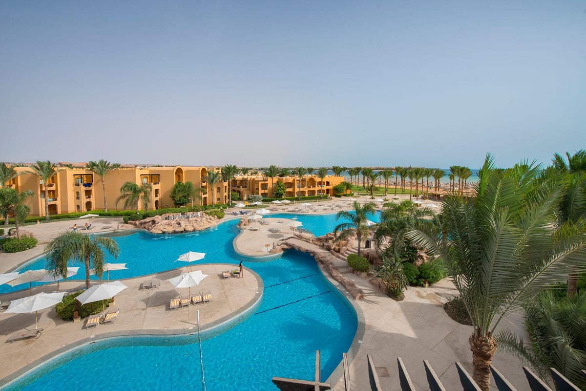Stella Beach Resort & Spa Makadi Bay pool area with curved pools and palm trees.
