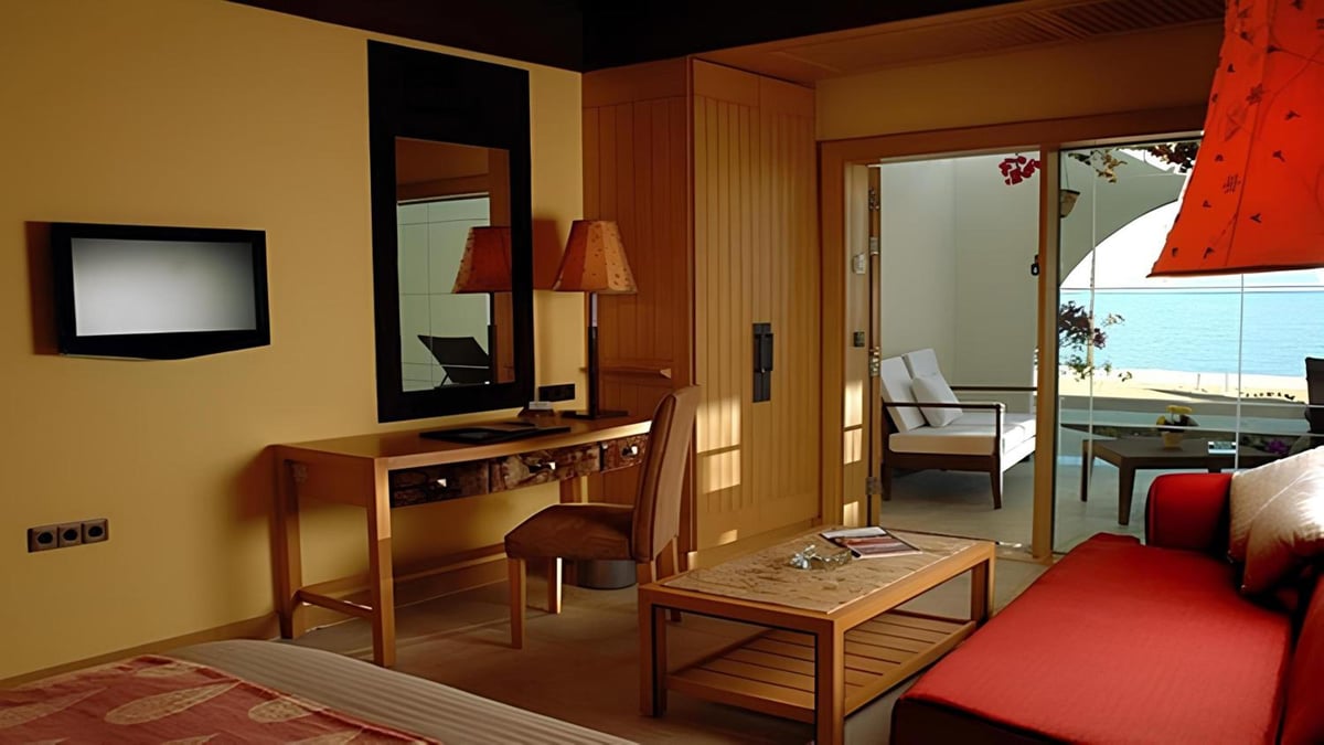Retac Qunay Dahab Resort & Spa guest room with a red sofa and glass doors to a balcony.